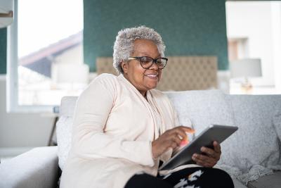 Grey haired older lady with glasses using tablet to study